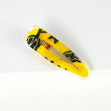 Barrette écorespondable en forme de goutte en résine recouvrant un morceau de chute de pagne wax recyclé