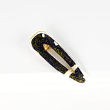 barrette en forme de goutte de larme faite en résine encastrant un retaille de tissu africain bogolan bleu et blanc et des paillettes dorées