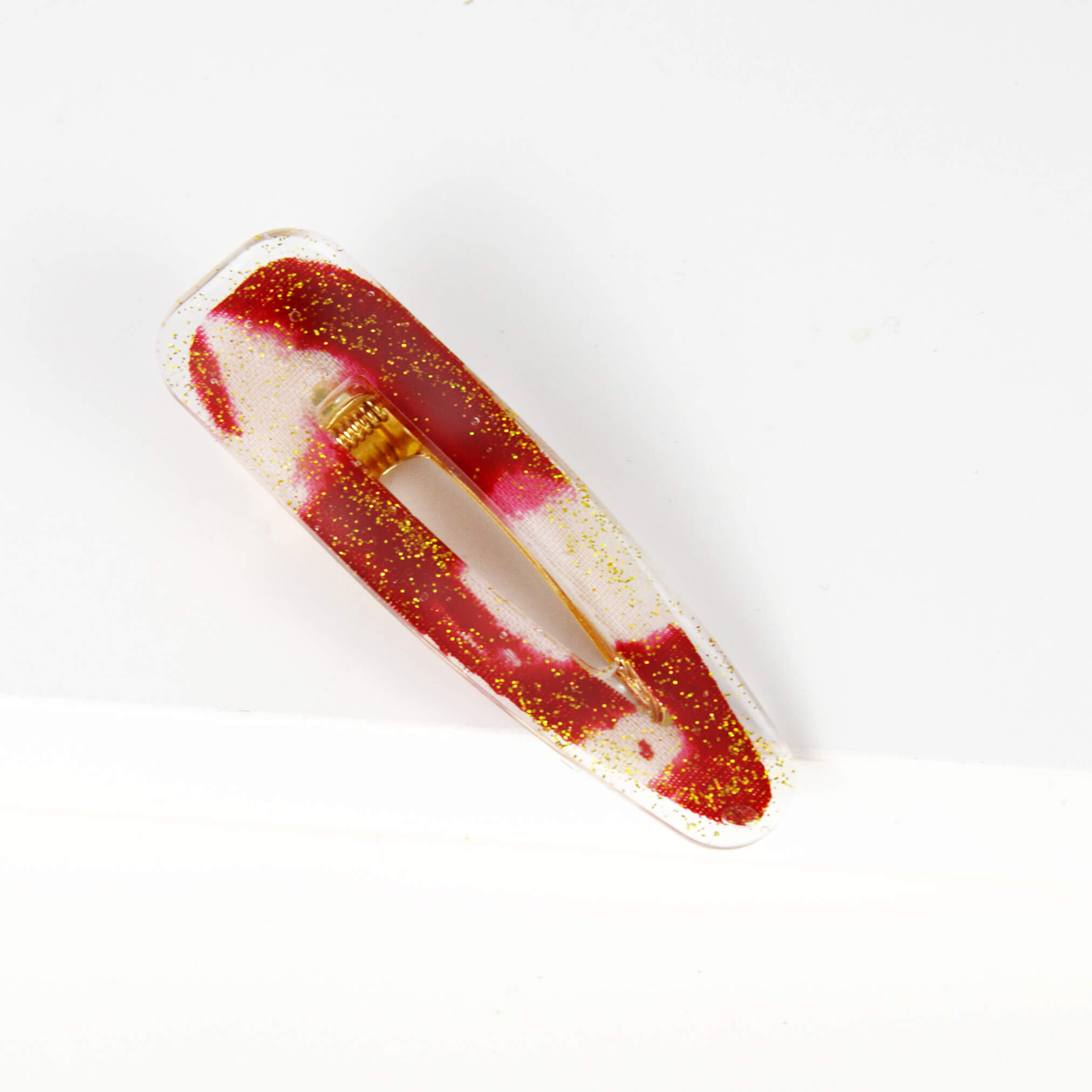 barrette en forme de goutte de larme avec un morceau de retaille de pagne wax rouge et blanc encastré dans de la résine