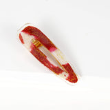 barrette en forme de goutte de larme avec un morceau de retaille de pagne wax rouge et blanc encastré dans de la résine