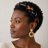 Femme noire aux cheveux crépus courts portant un serre-tête tressé noir et brun en mousseline de soie inspiré du bogolan africain