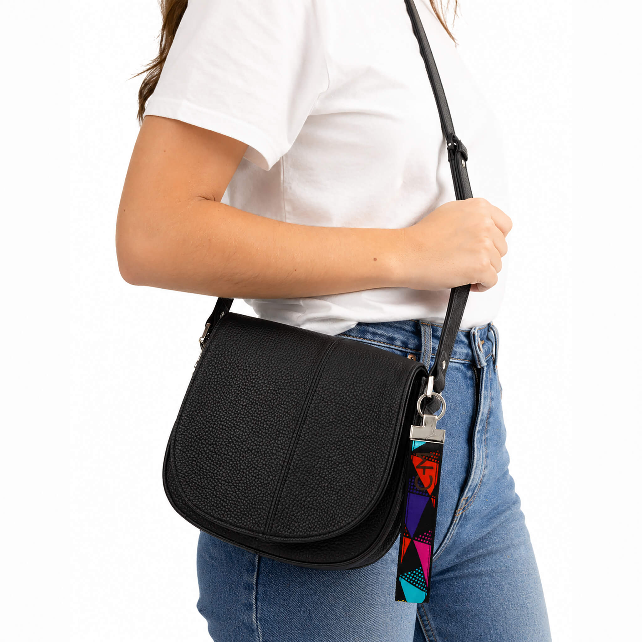 Porte-clé en tissu multicolore accroché à un sac noir porté à l’épaule, mise en situation lifestyle