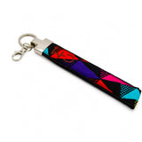 Porte-clé en pagne wax multicolore aux motifs rouges, mauves, bleus et roses sur fond blanc, vue en angle