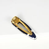 handmade ecodriendly teardrop barrette made of blue and white african print mud cloth fabric and resin containig gold glitter equiped with an alligator clip