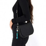 Porte-clé en tissu turquoise et noir accroché à un sac noir porté en bandoulière, Québec Coo-Mon