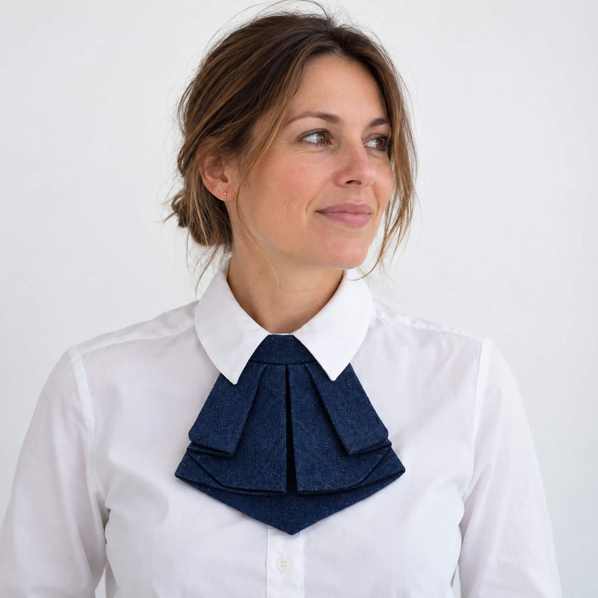 Femme portant une cravate courte style jabot en denim bleu jeans avec une chemise blanche