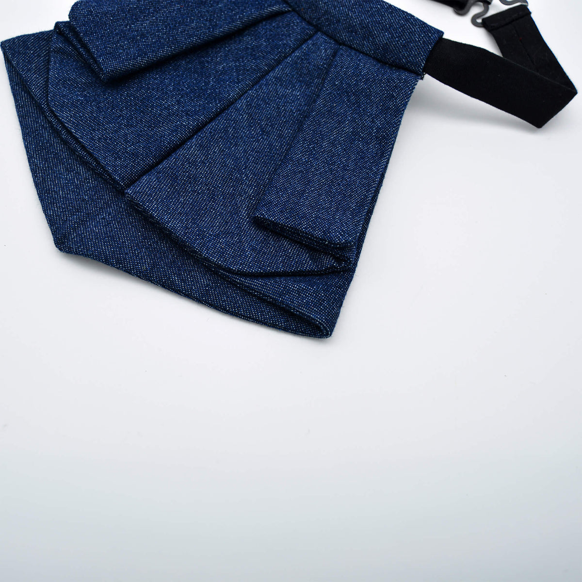 Vue de trois quarts de la cravate courte en denim bleu jeans montrant le volume et les plis structurés