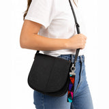 Porte-clé en tissu multicolore accroché à un sac noir porté à l’épaule, mise en situation lifestyle